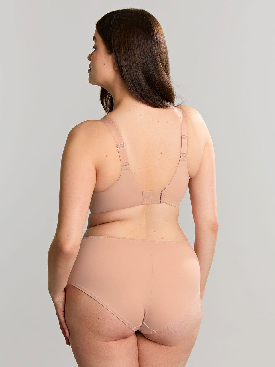 Model wearing a beige Bliss bra and matching deep brief, back three-quarter view