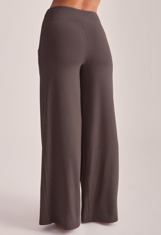A person wearing high-waisted, wide-leg lounge pants in a solid dark taupe-brown color.