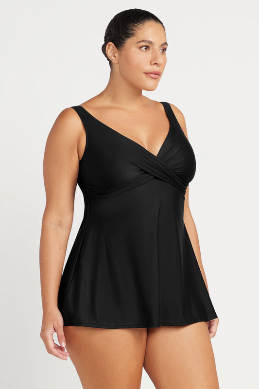 Woman wearing a black swim-dress on a white background