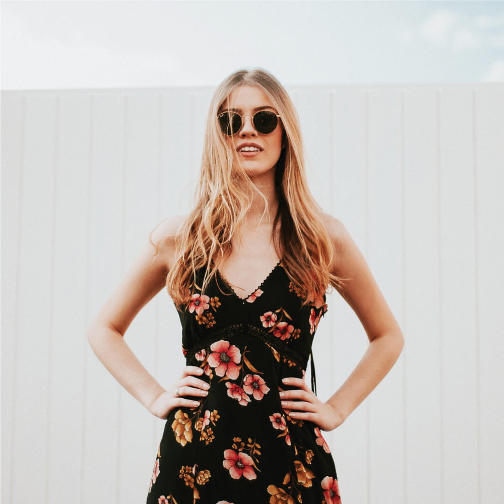 Woman wearing a dress and sunglasses with hands on her hips