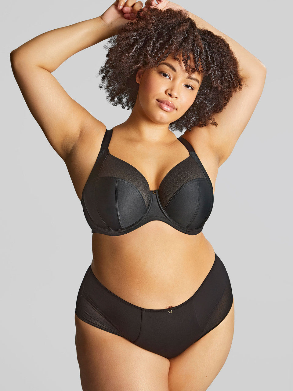 Woman wearing a black bra and underwear set against a gray background