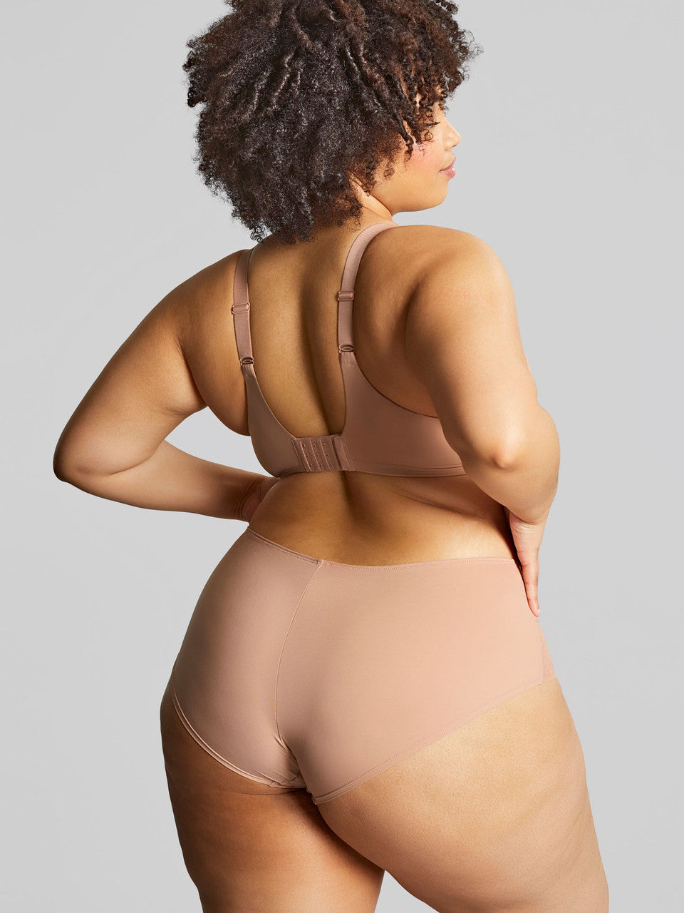 Woman wearing a beige shapewear set on a gray background
