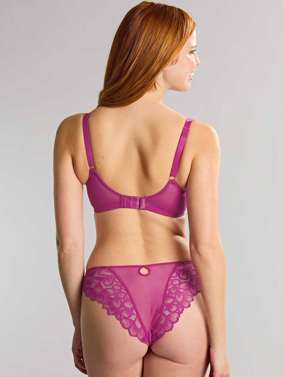 Woman wearing a magenta lingerie set on a gray background