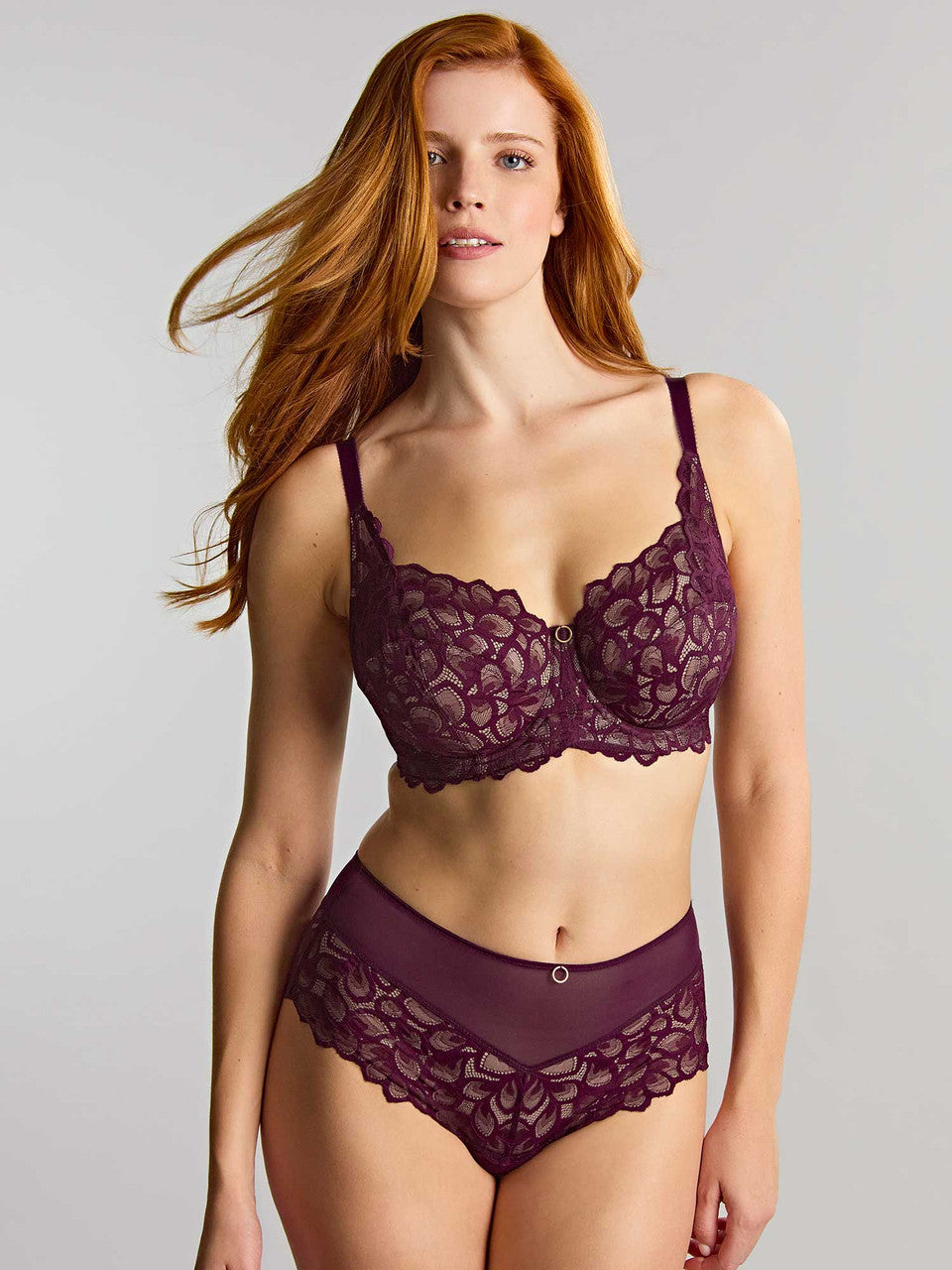 A woman modeling a matching lace lingerie set in a deep plum color.
