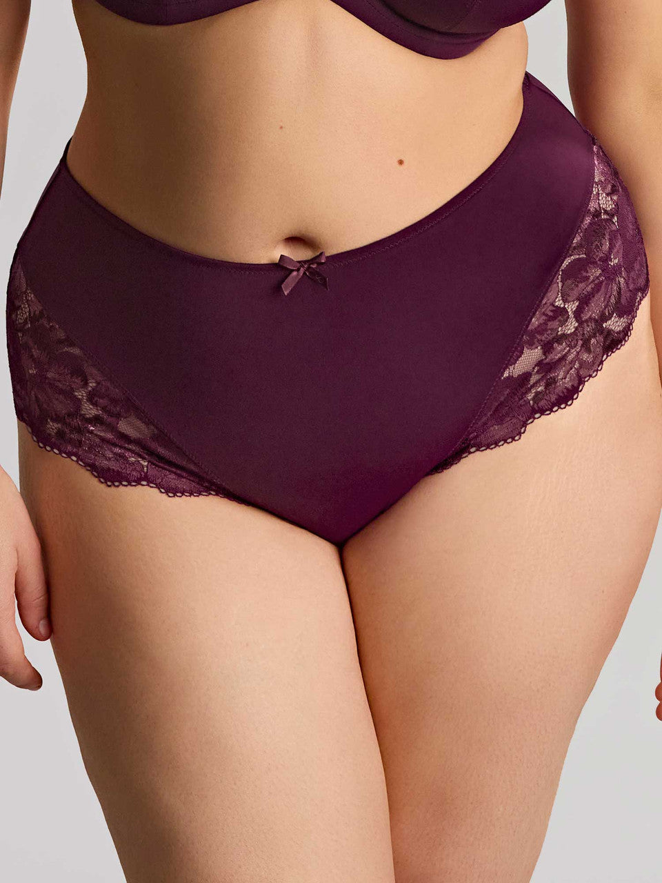 Model wearing high-waisted plum lace panties shown against a light gray studio background.