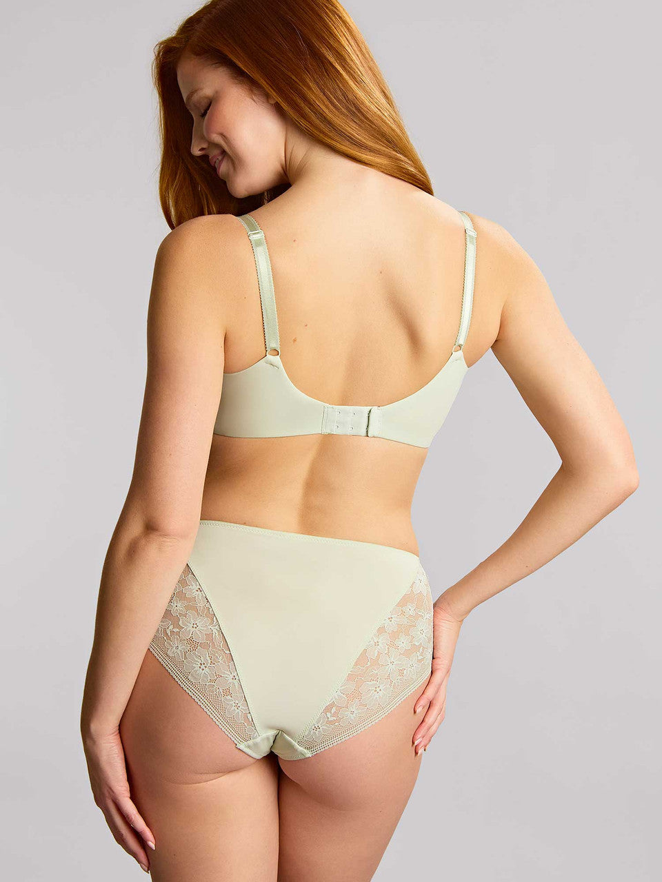 Woman wearing a light green bra and panties set on a gray background