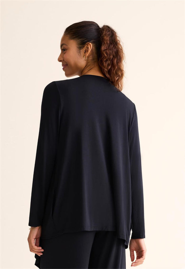 Woman wearing a black long-sleeve top against a beige background