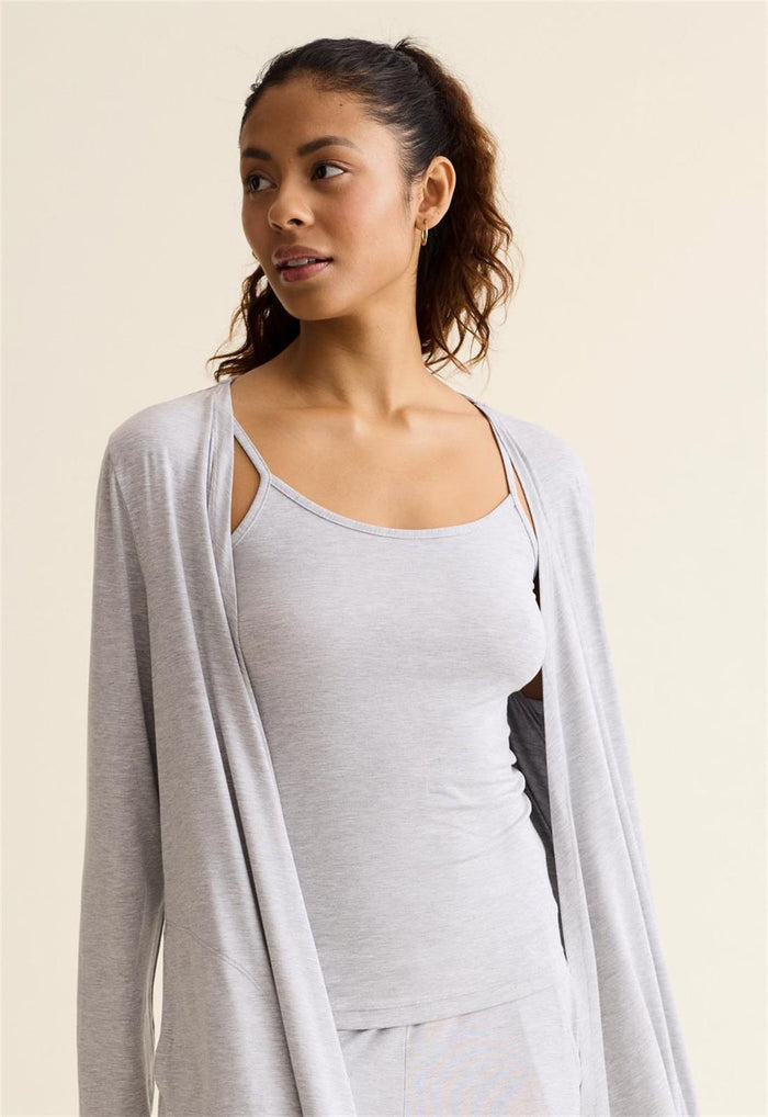 Woman wearing a light gray cardigan over a white top on a beige background