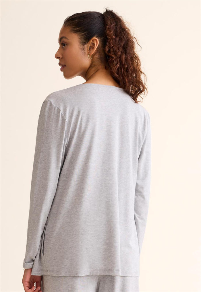 Woman wearing a light gray long-sleeve top and pants on a beige background