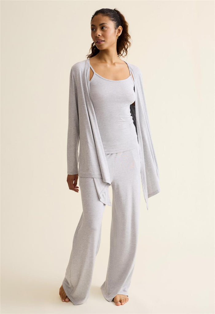 Woman wearing a light gray outfit with a matching cardigan on a beige background