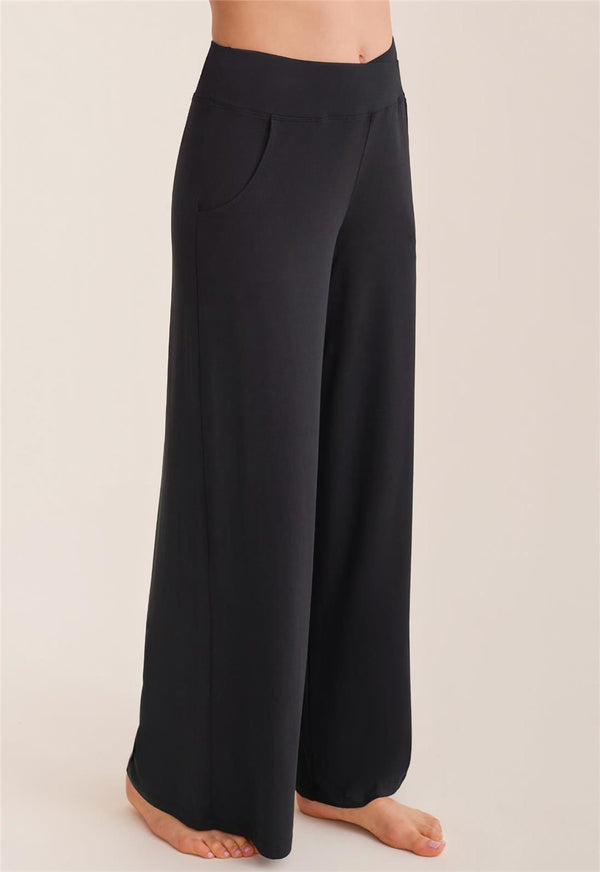 Black wide-leg pants worn by a person on a beige background