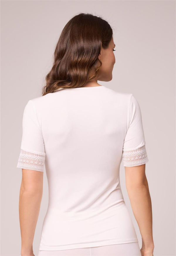 Woman wearing a white top with lace sleeves on a plain background