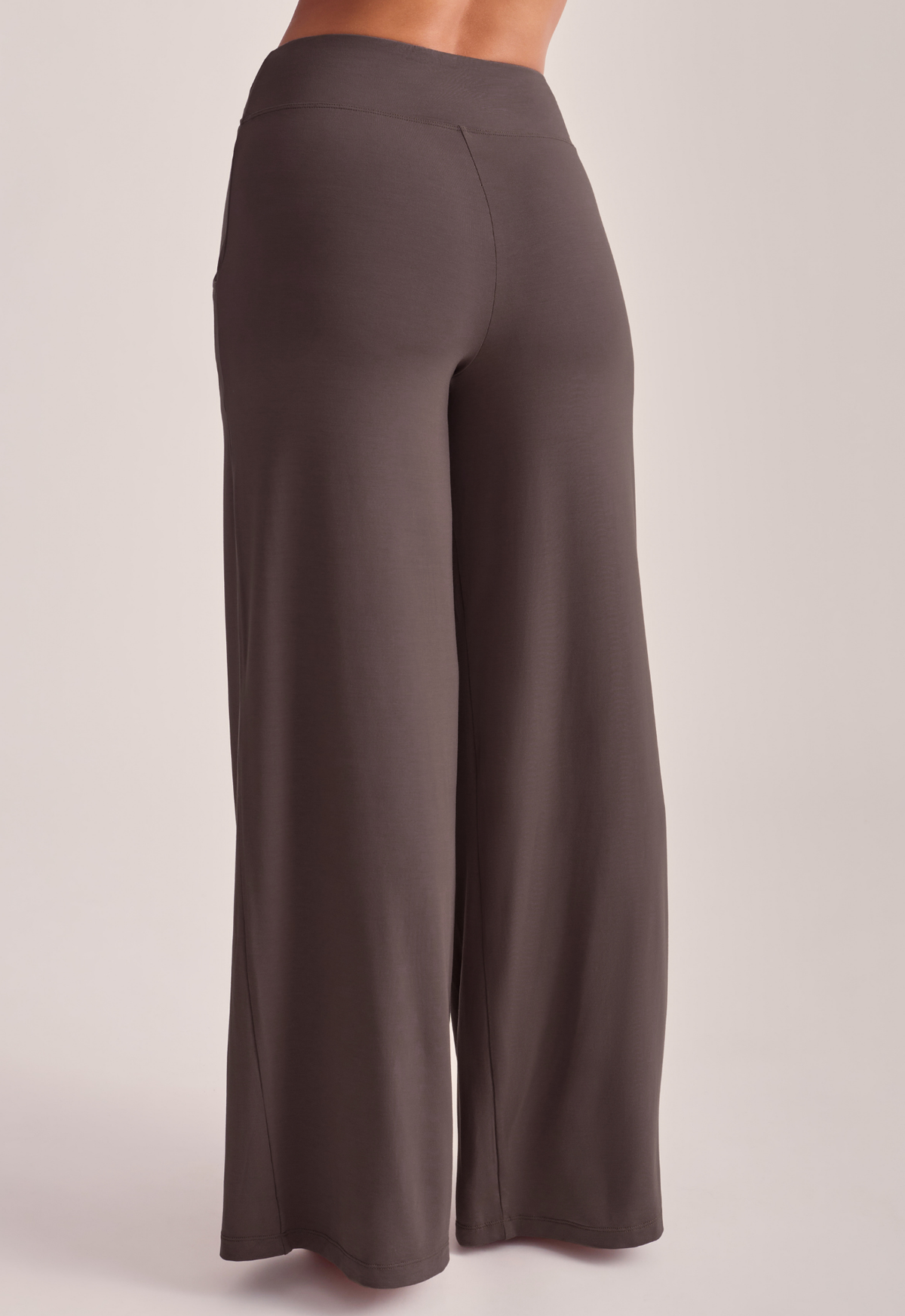 A person wearing high-waisted, wide-leg lounge pants in a solid dark taupe-brown color.