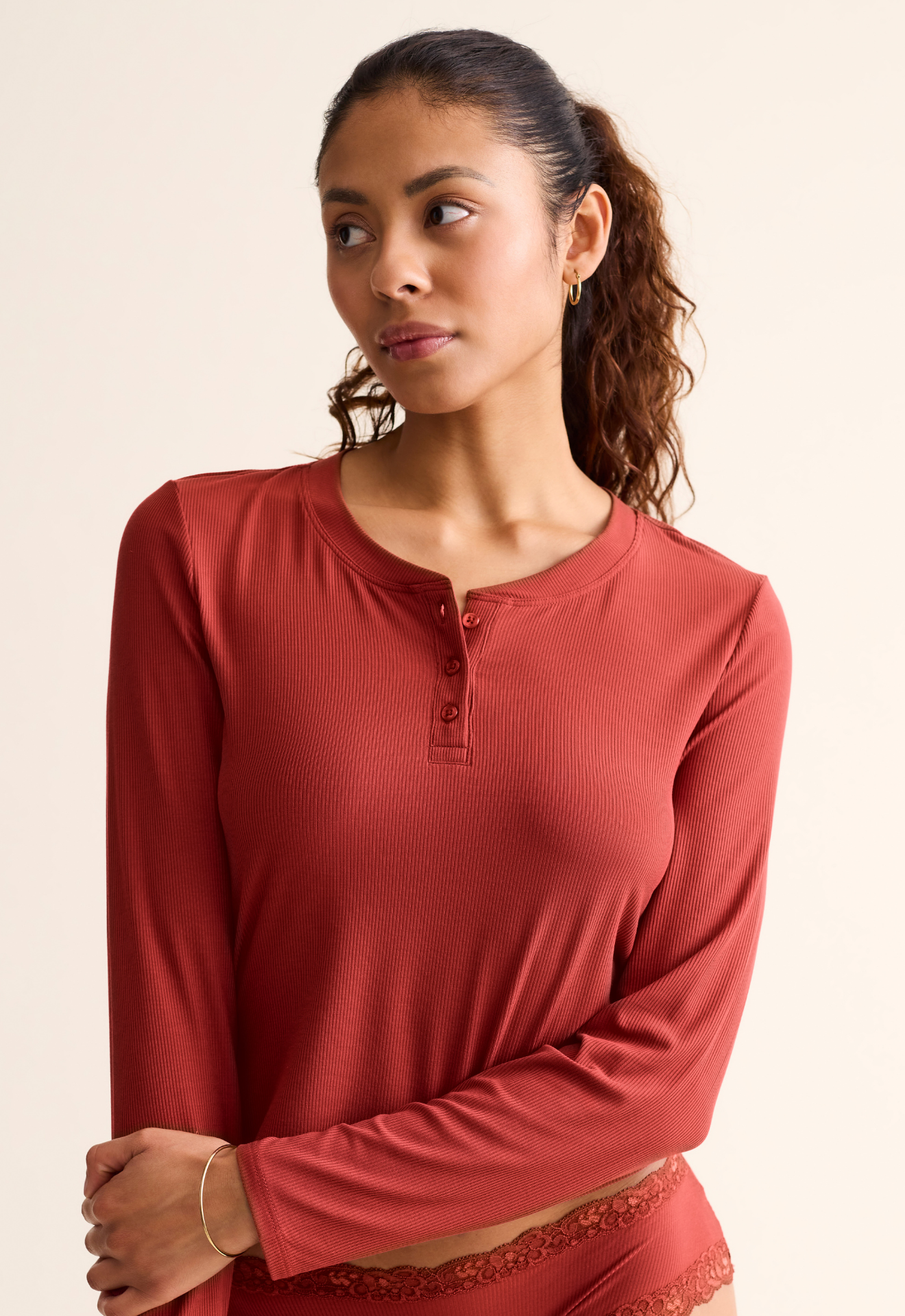 Woman wearing a red long-sleeve top against a beige background