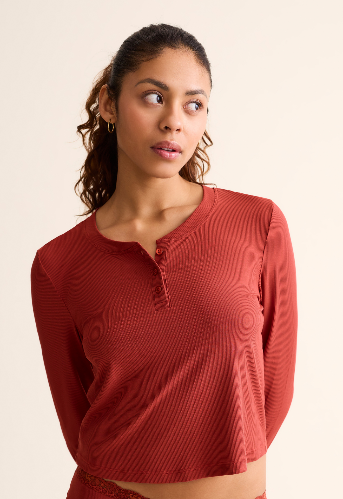 Woman wearing a red long-sleeve top against a beige background