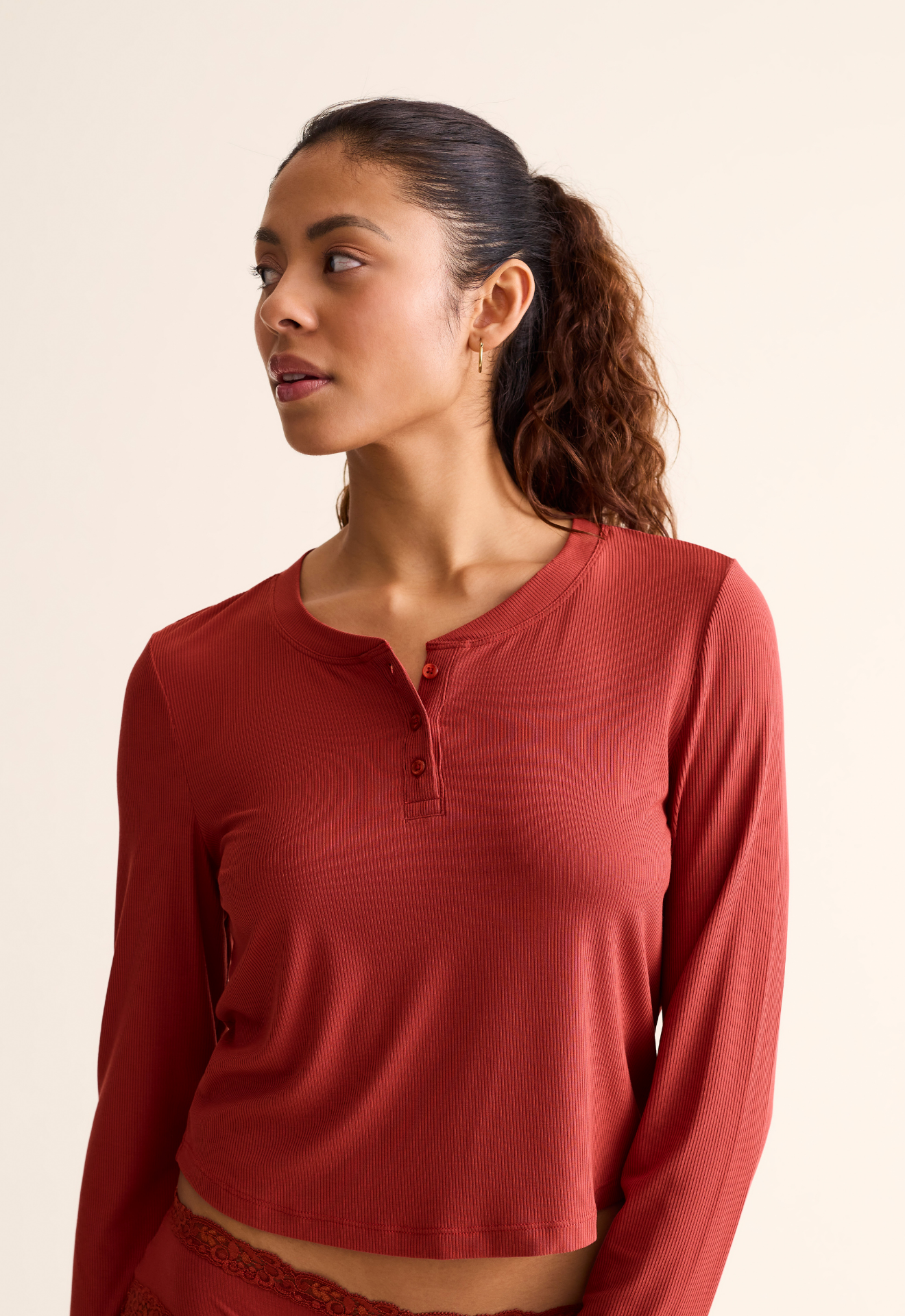 Woman wearing a red long-sleeve top against a beige background