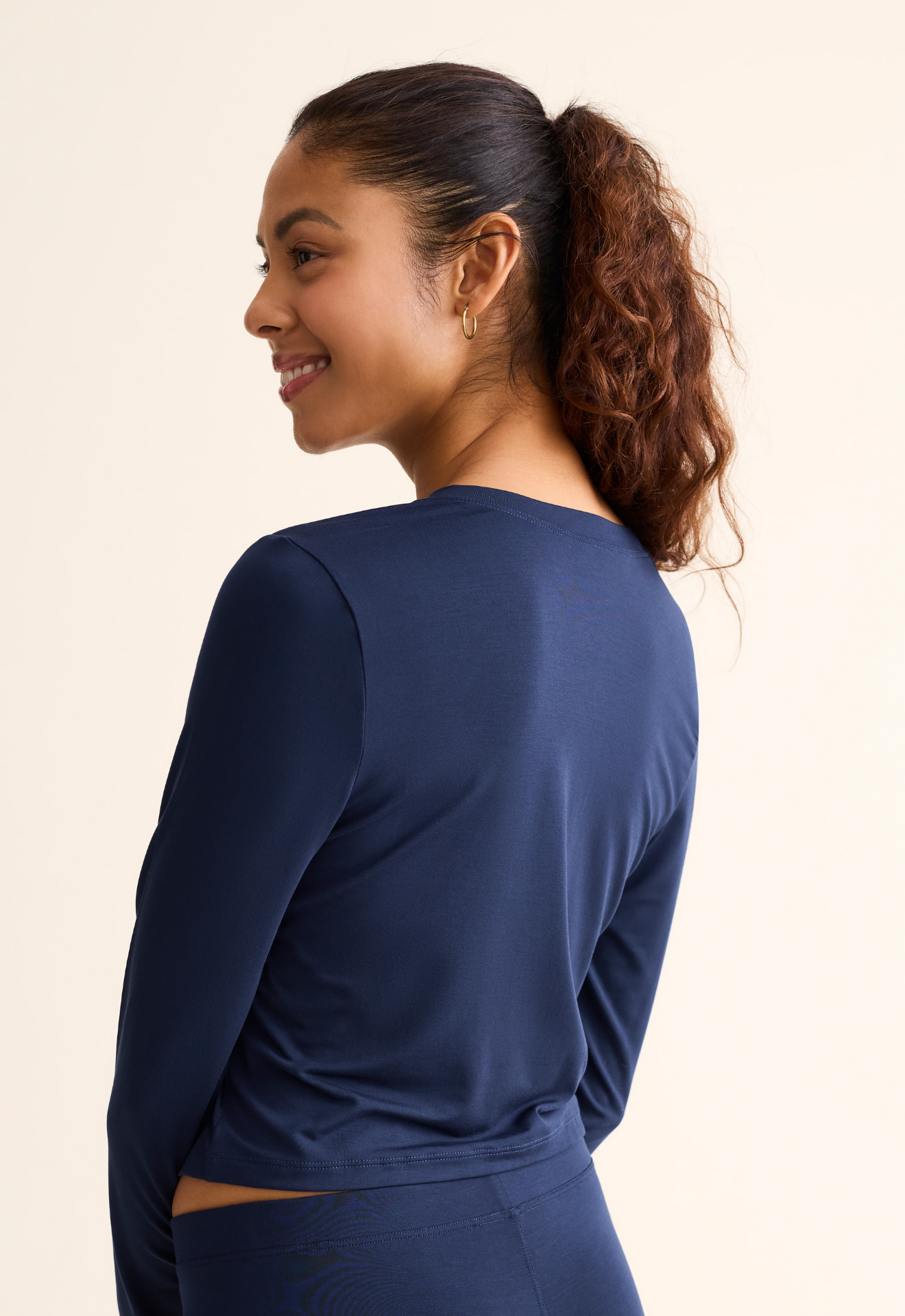 Woman wearing a blue long-sleeve top against a beige background