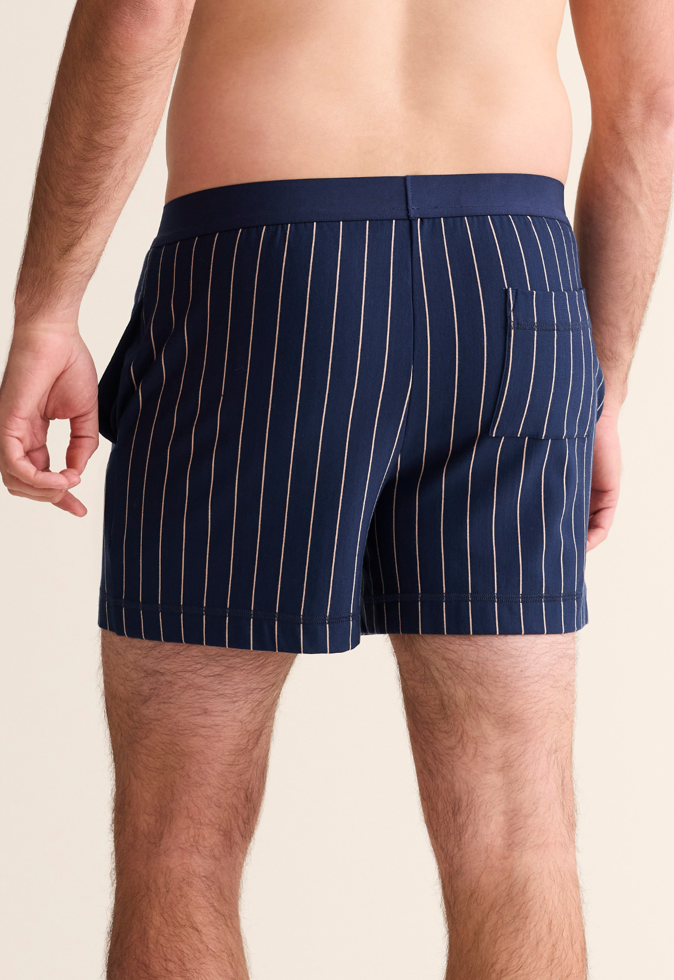 Navy pinstripe boxer briefs worn by a person on a beige background
