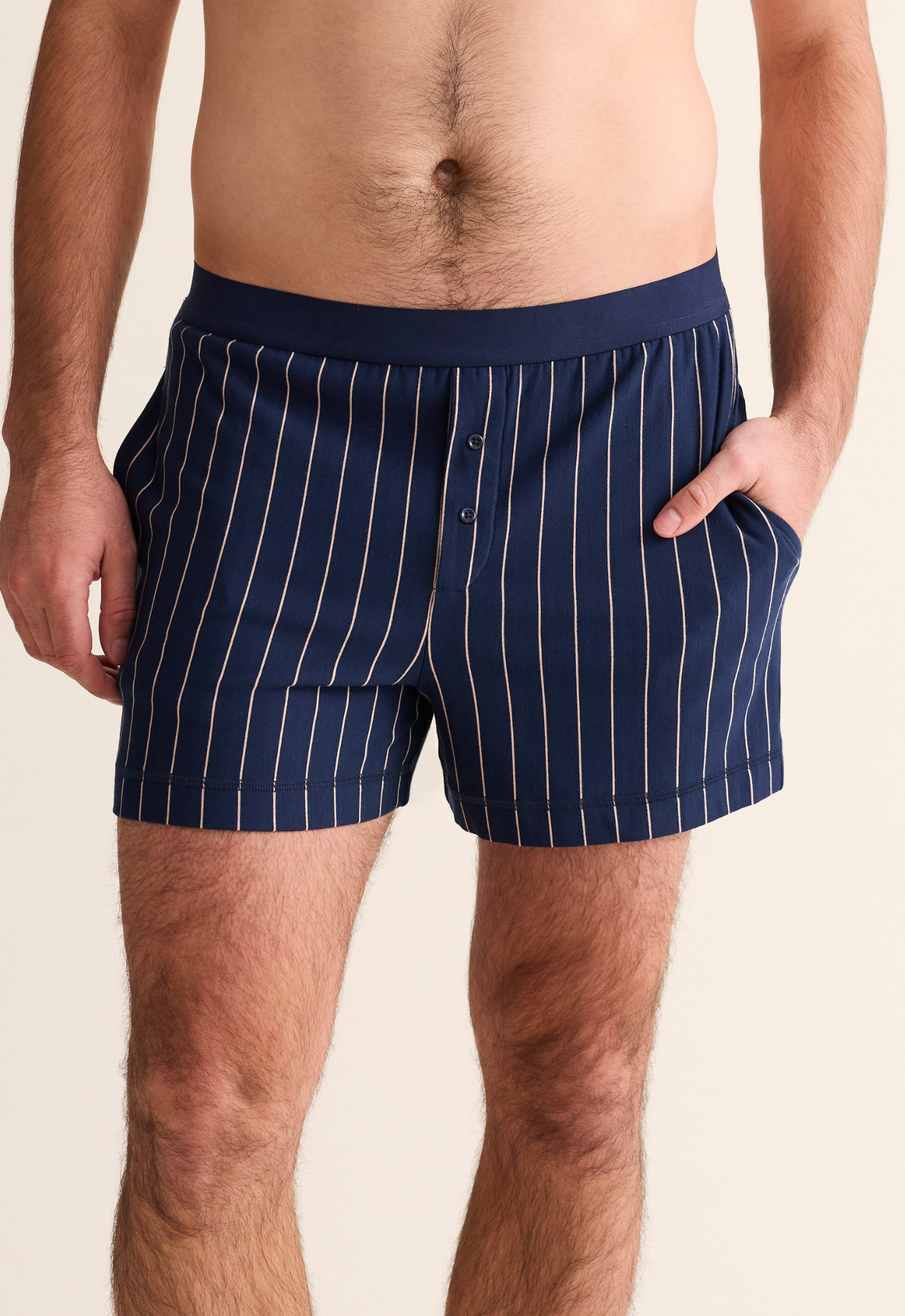 Navy pinstripe boxer shorts worn by a person on a beige background