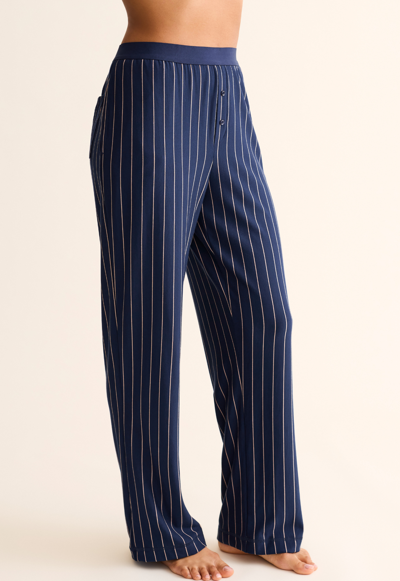 Navy pinstripe pants worn by a person on a beige background