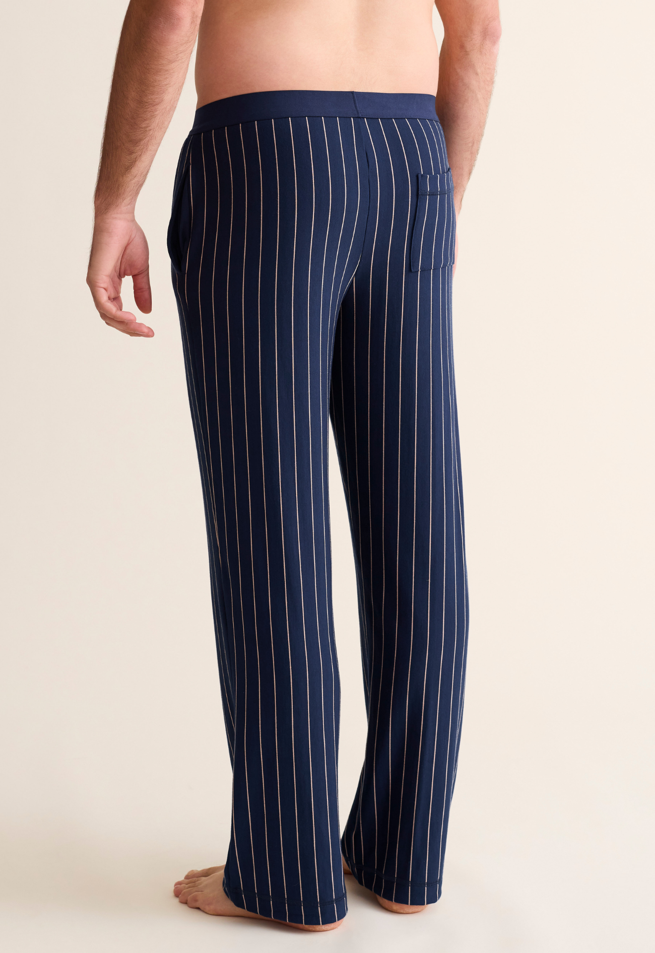 Navy pinstripe pants worn by a person on a beige background