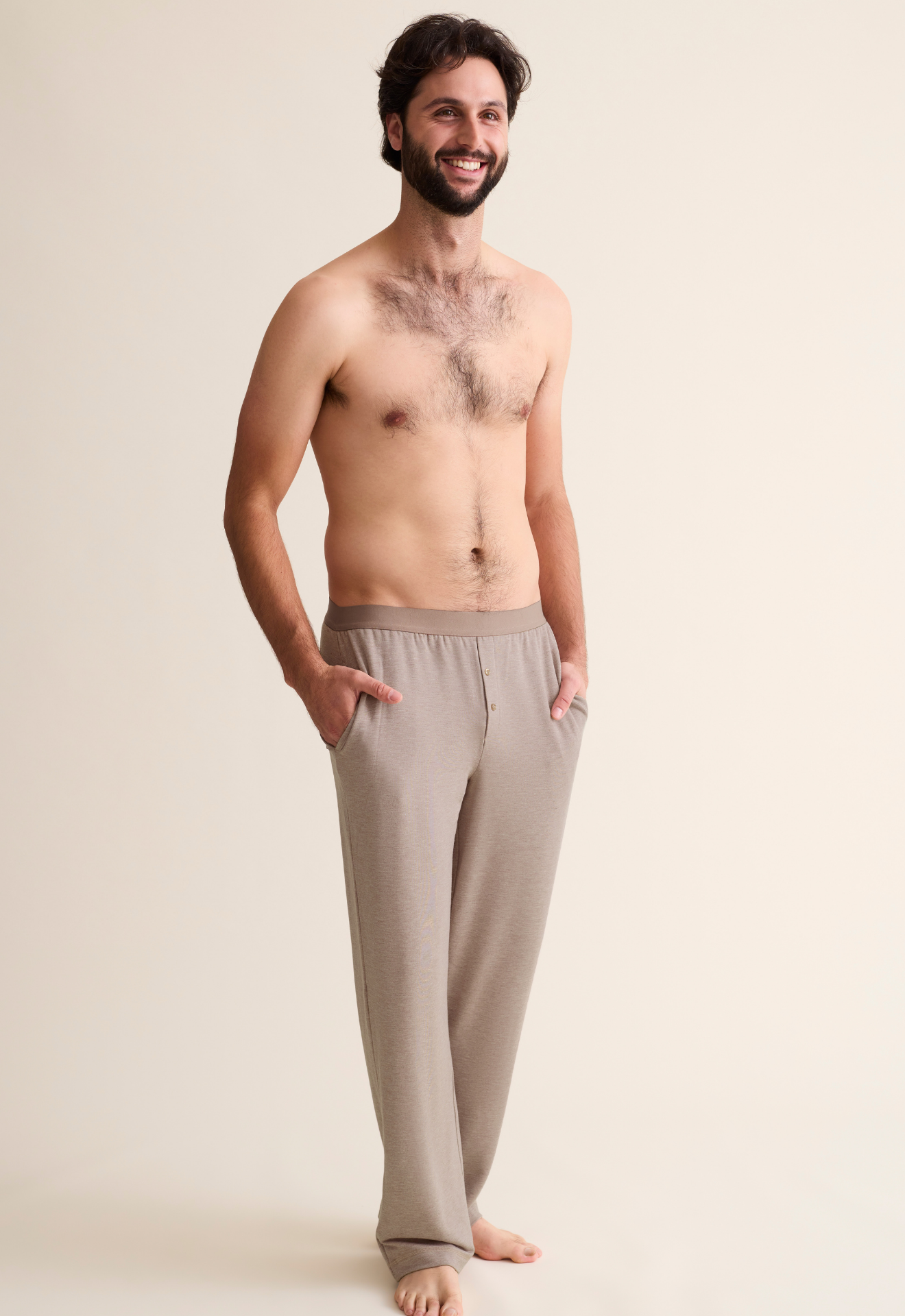 Man wearing beige pajama pants against a plain background