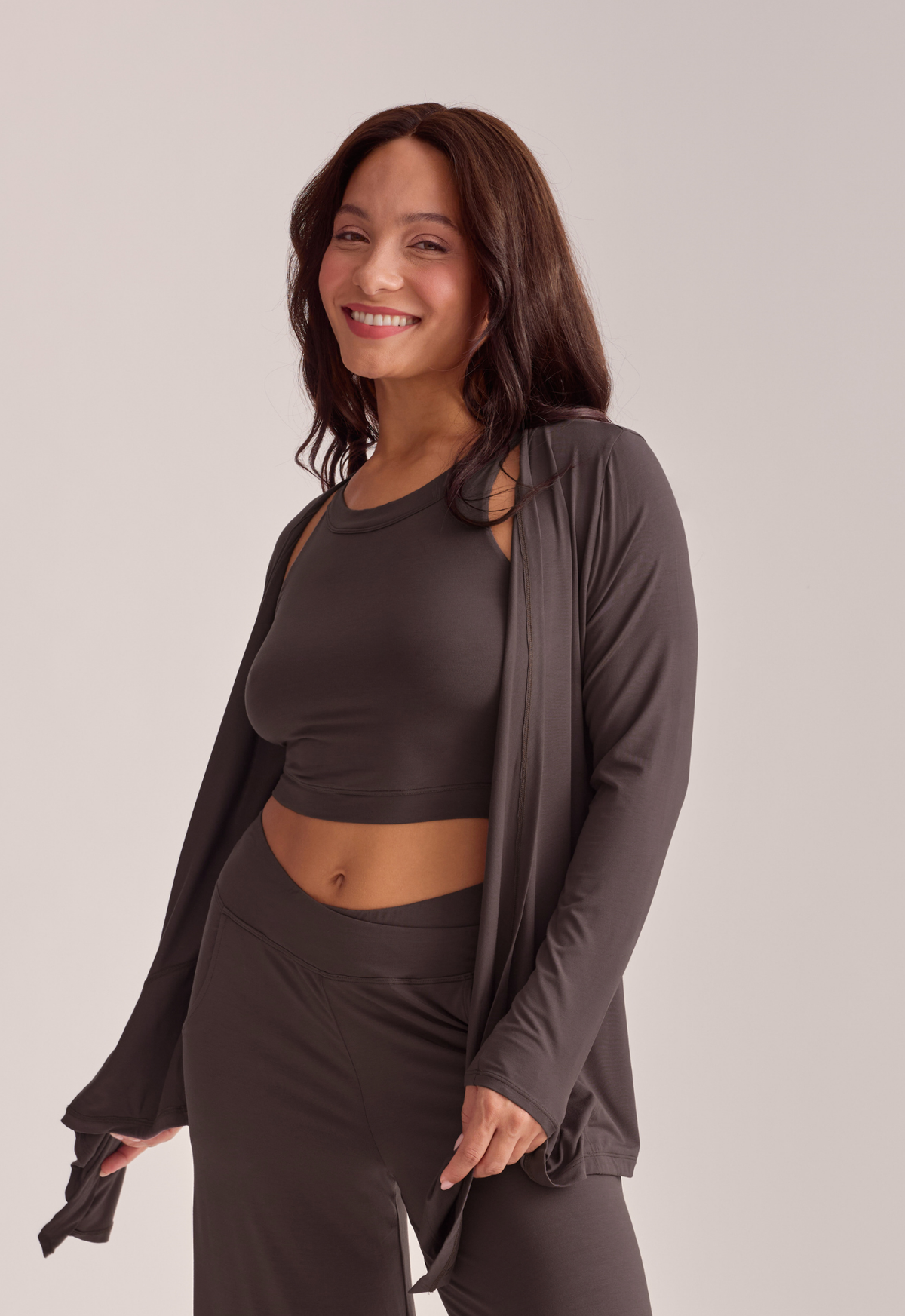 A woman modeling a dark brown lounge set, set against a solid light gray background.
