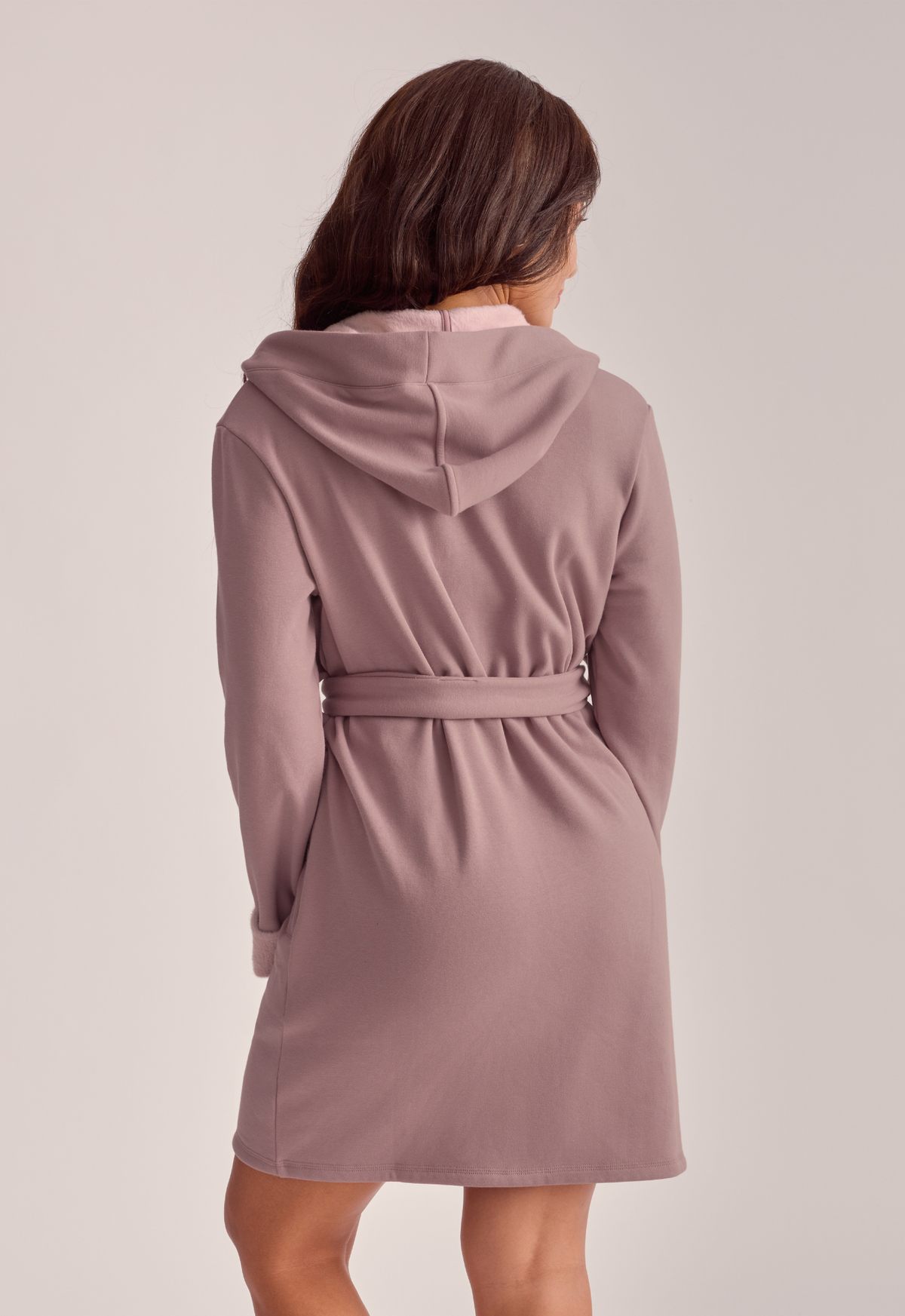 A woman shown from the back wearing a dusty mauve hooded robe
