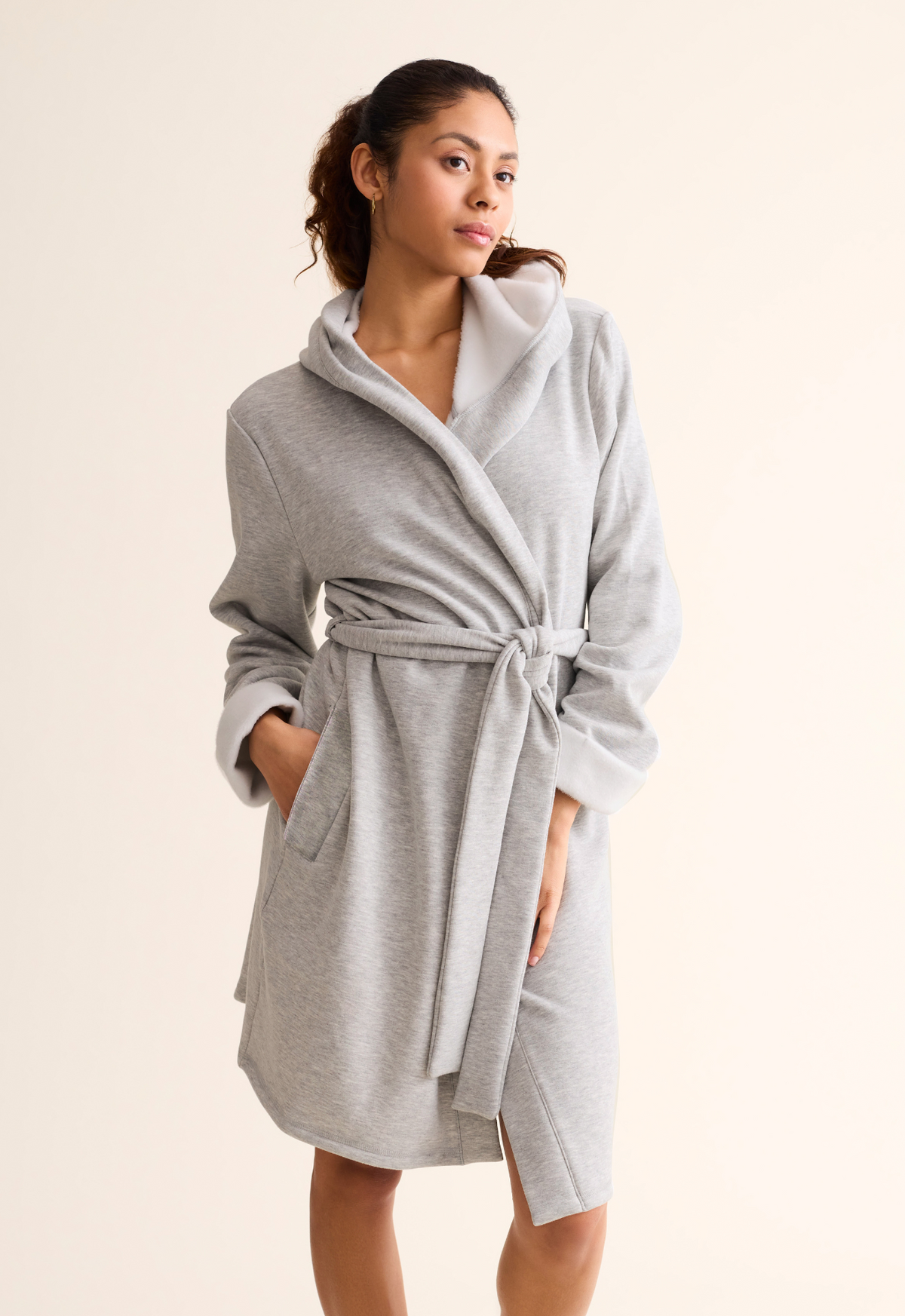 Woman wearing a gray robe against a beige background