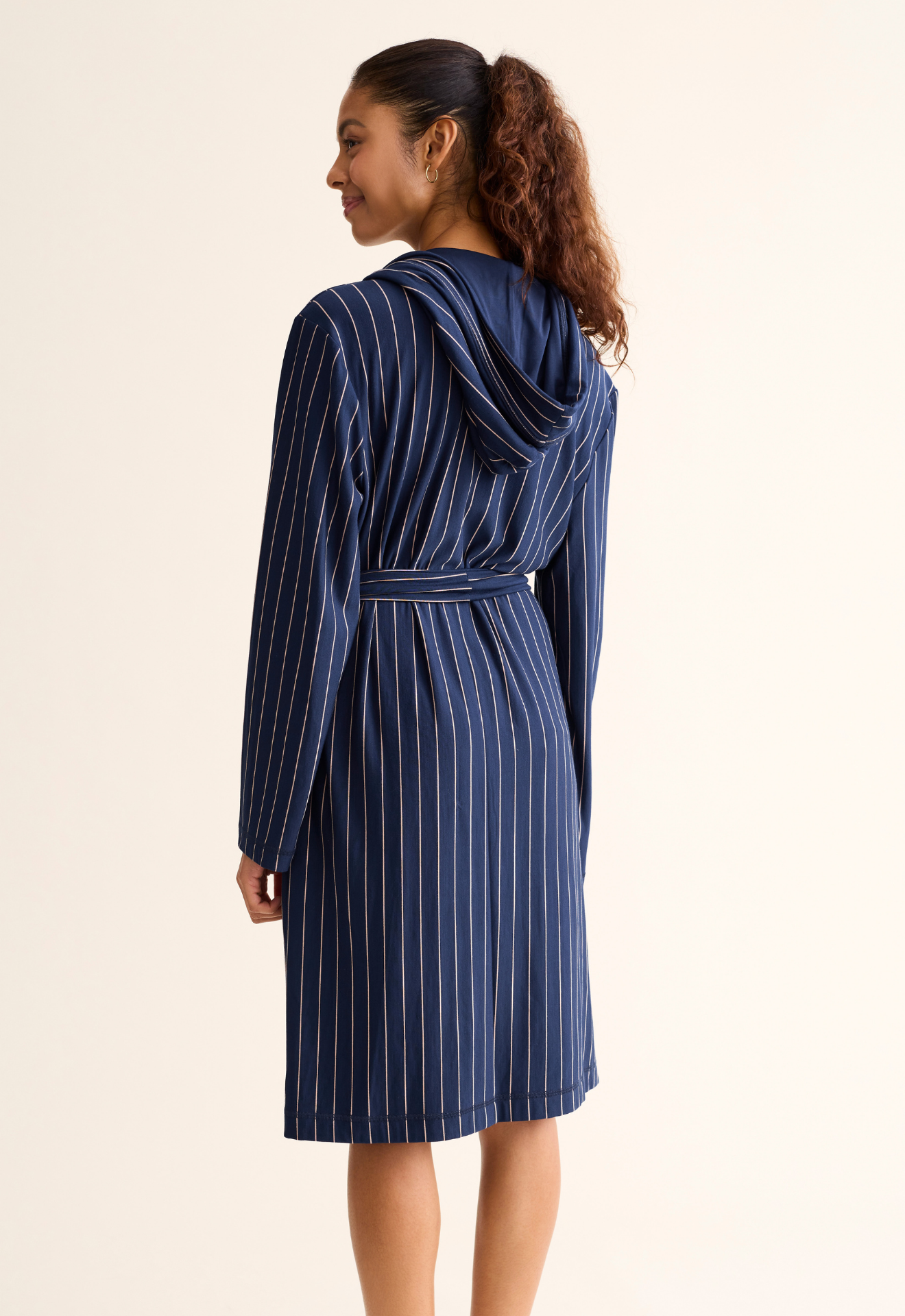 Woman wearing a blue striped robe on a beige background