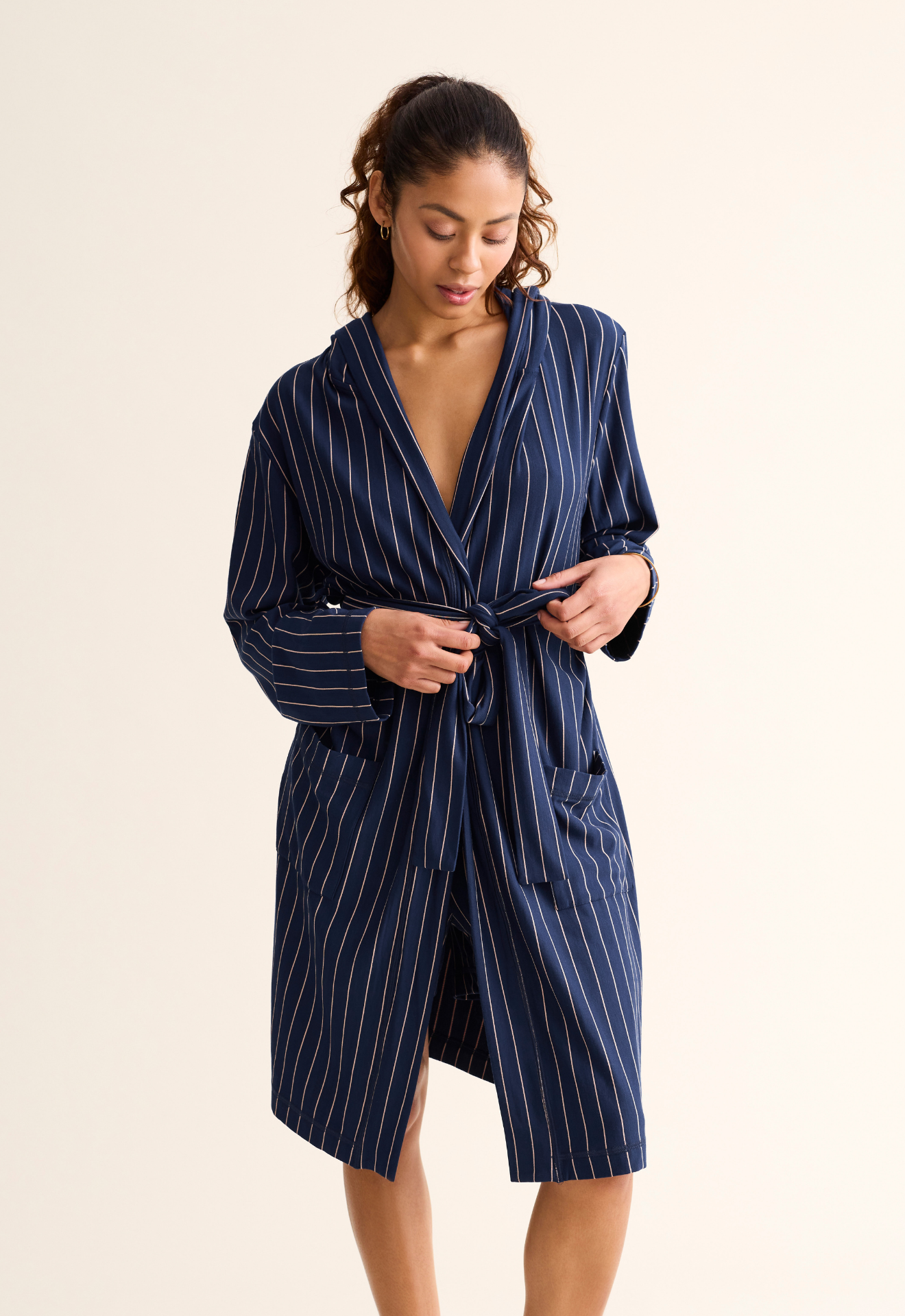 Woman wearing a navy pinstripe robe against a beige background
