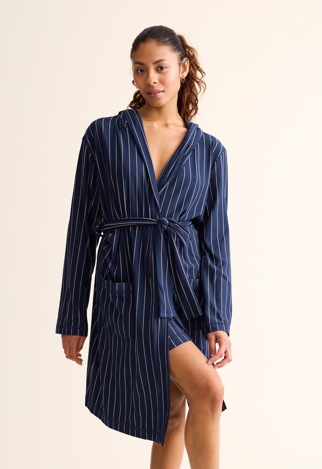 Woman wearing a navy pinstripe robe on a beige background