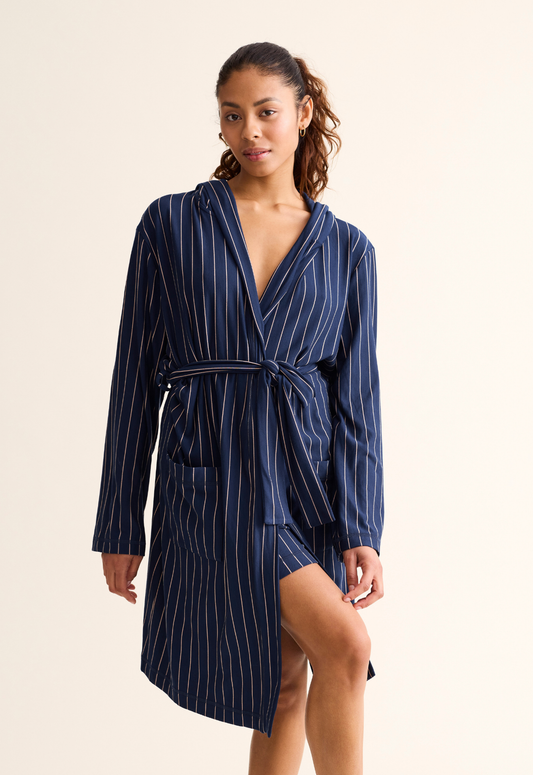 Woman wearing a navy pinstripe robe on a beige background