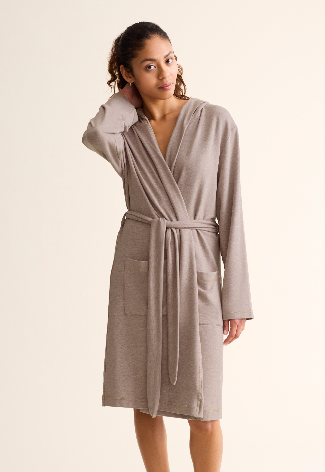 Woman wearing a beige robe against a plain background