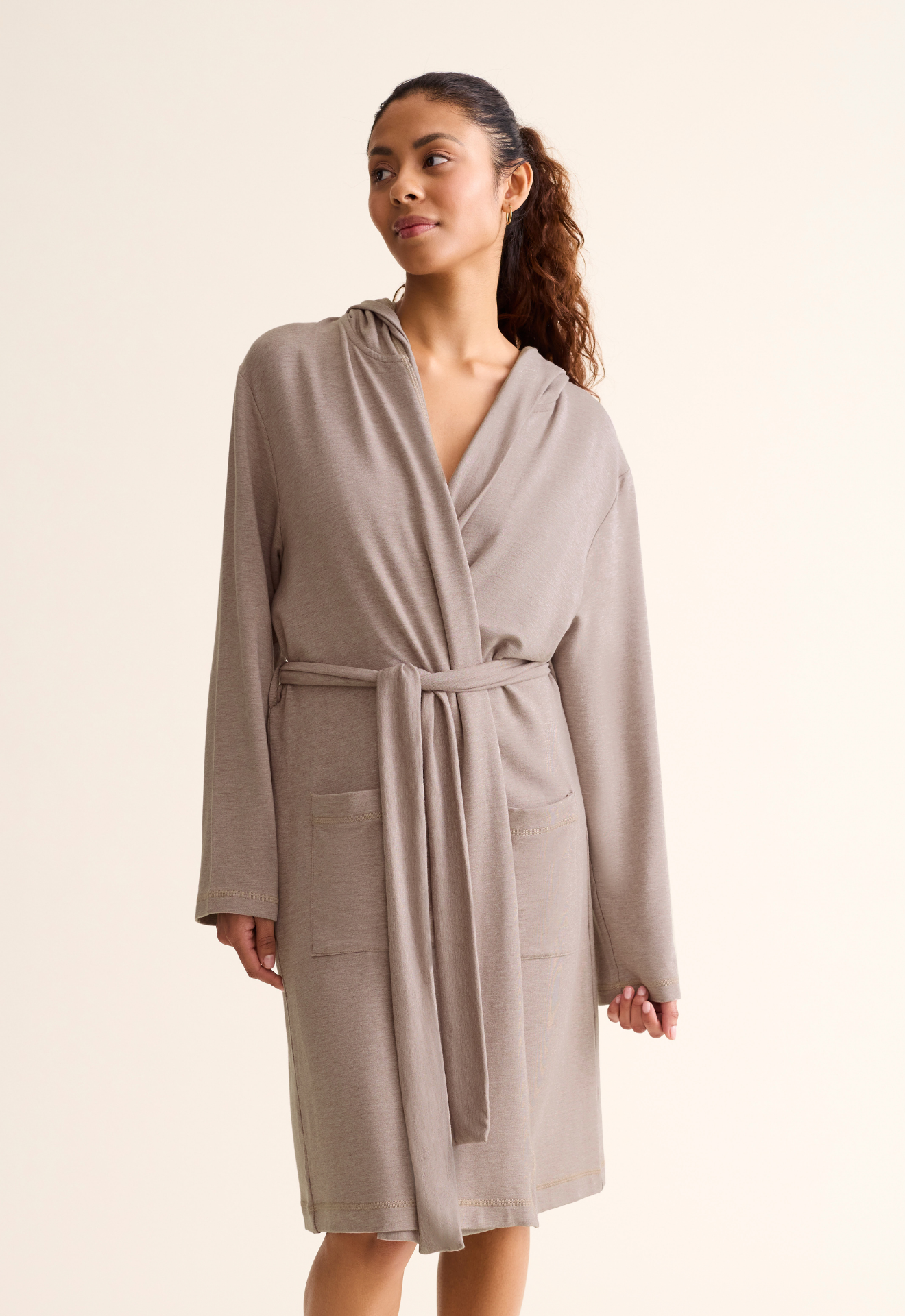 Woman wearing a beige robe against a plain background