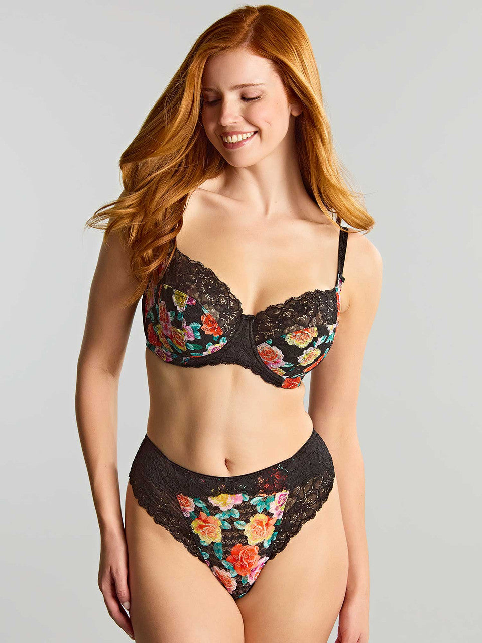 A woman modeling a two-piece lingerie set against a grey background.