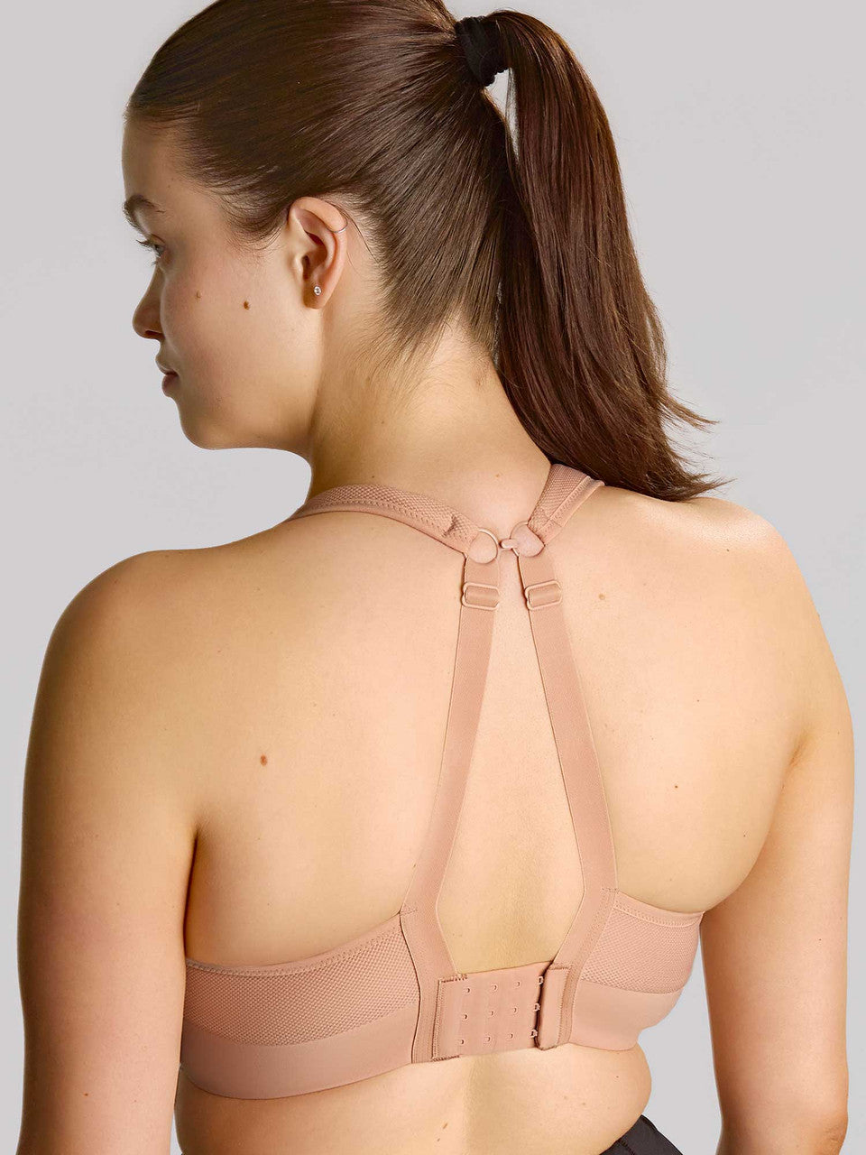 Woman wearing a beige sports bra against a plain background