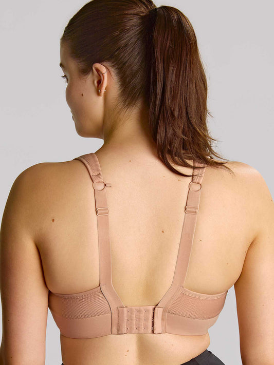 Woman wearing a beige bra against a plain background