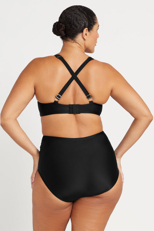 Person wearing a black swimsuit with criss-cross straps on a white background