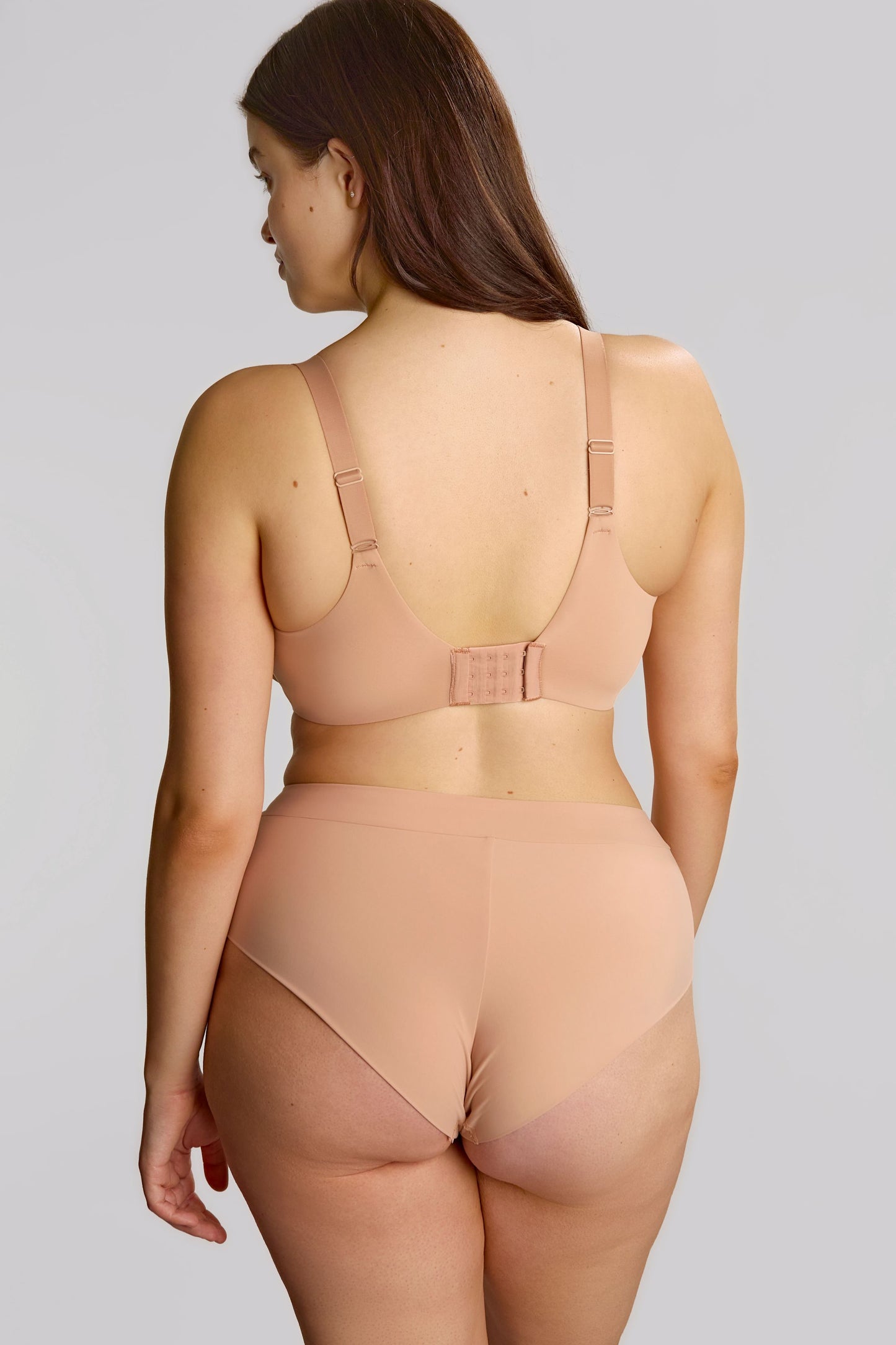 Woman wearing a beige lingerie set on a white background