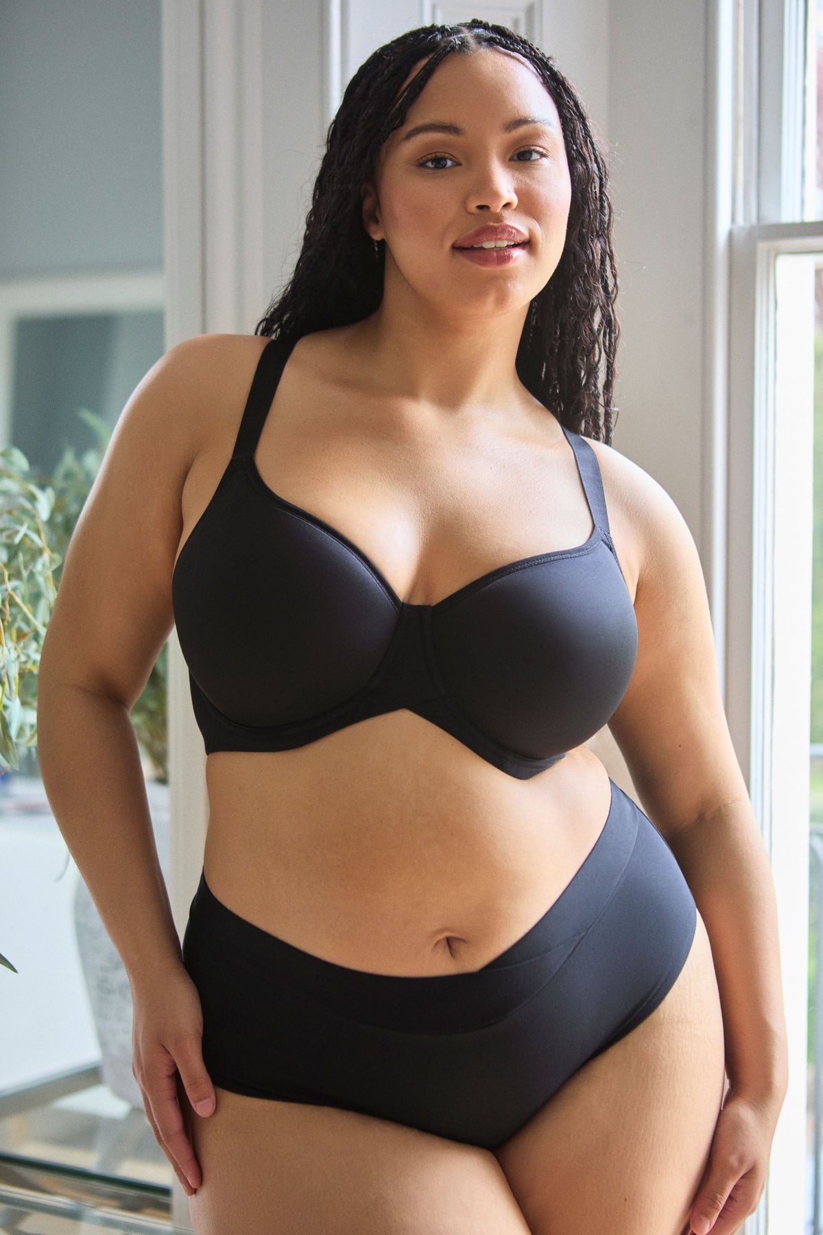Woman wearing a black bra set indoors with a neutral background