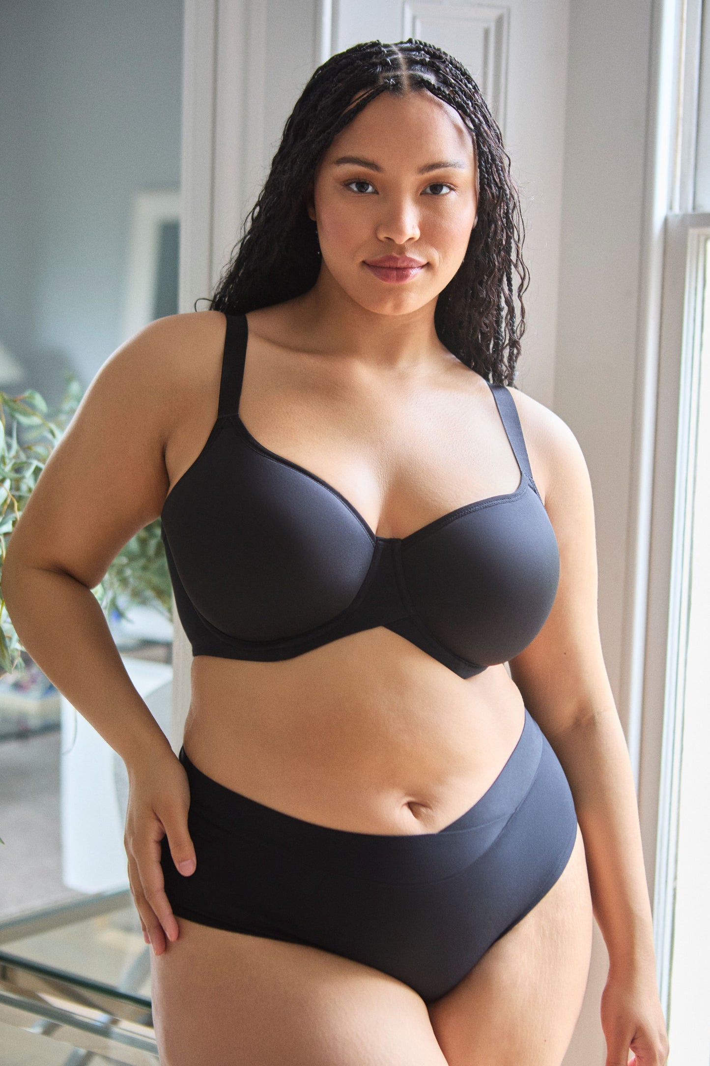 Woman wearing a black bra and panties set indoors.