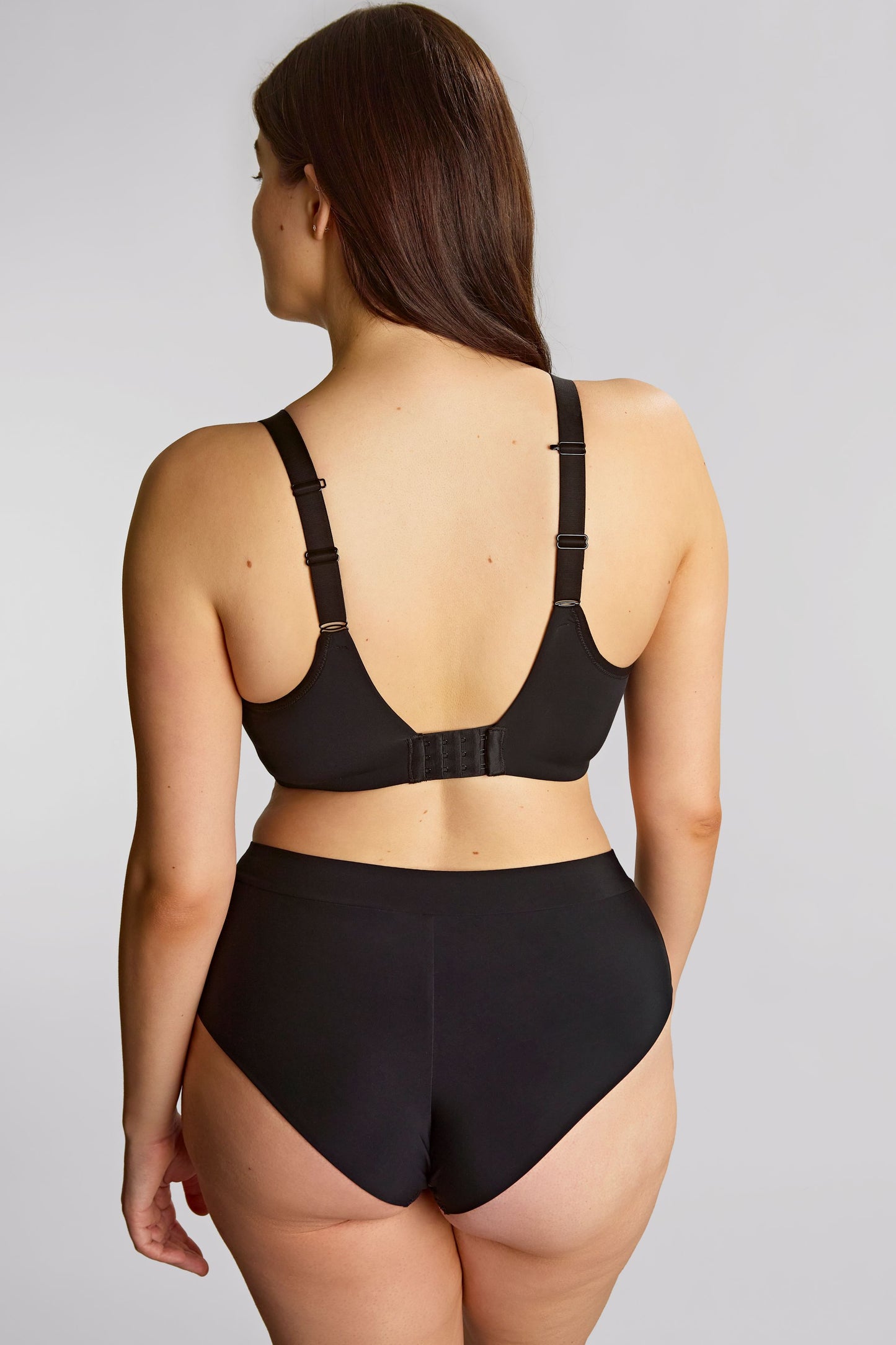 Woman wearing a black lingerie set on a plain background