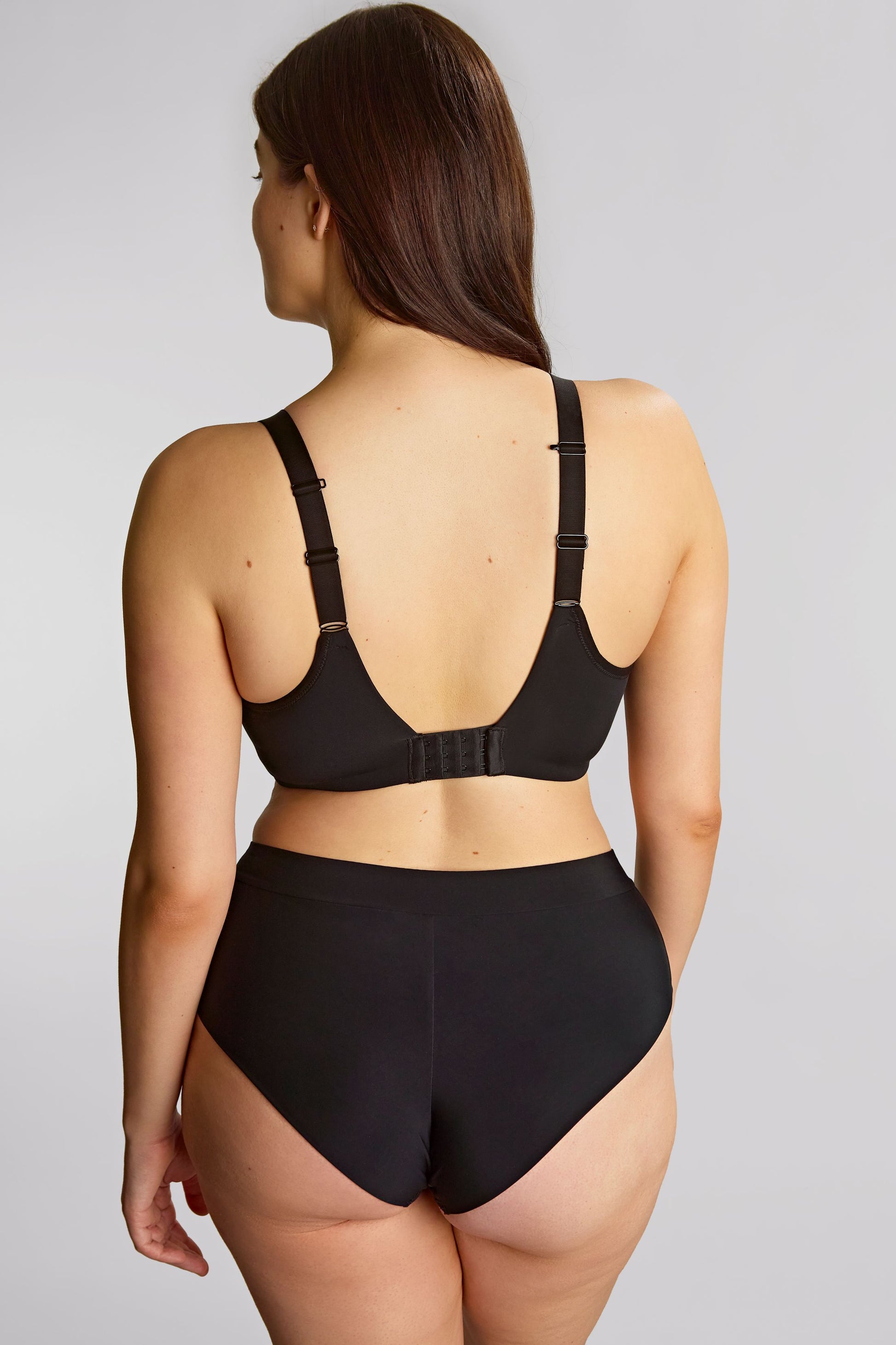 Woman wearing a black lingerie set on a plain background