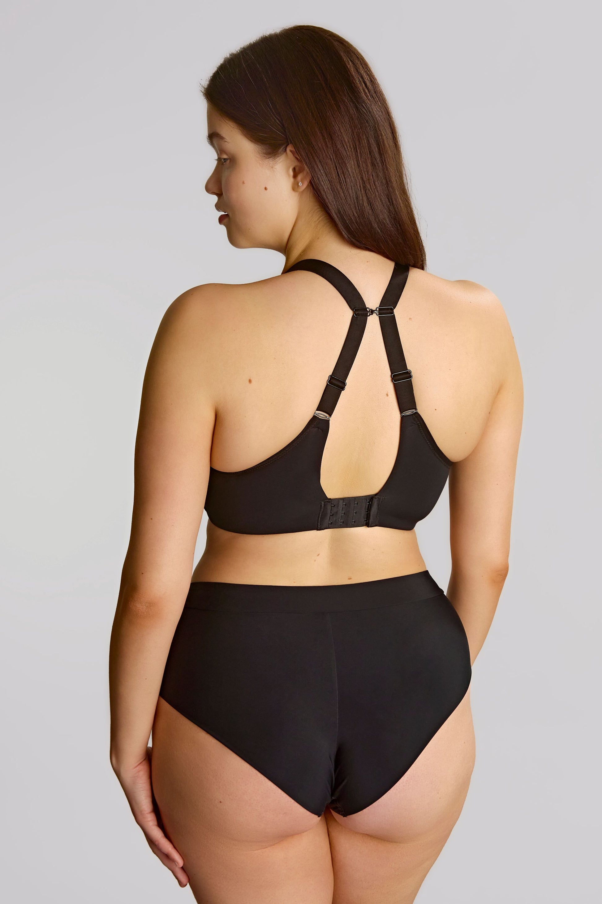 Woman wearing a black bra and panties set on a plain background
