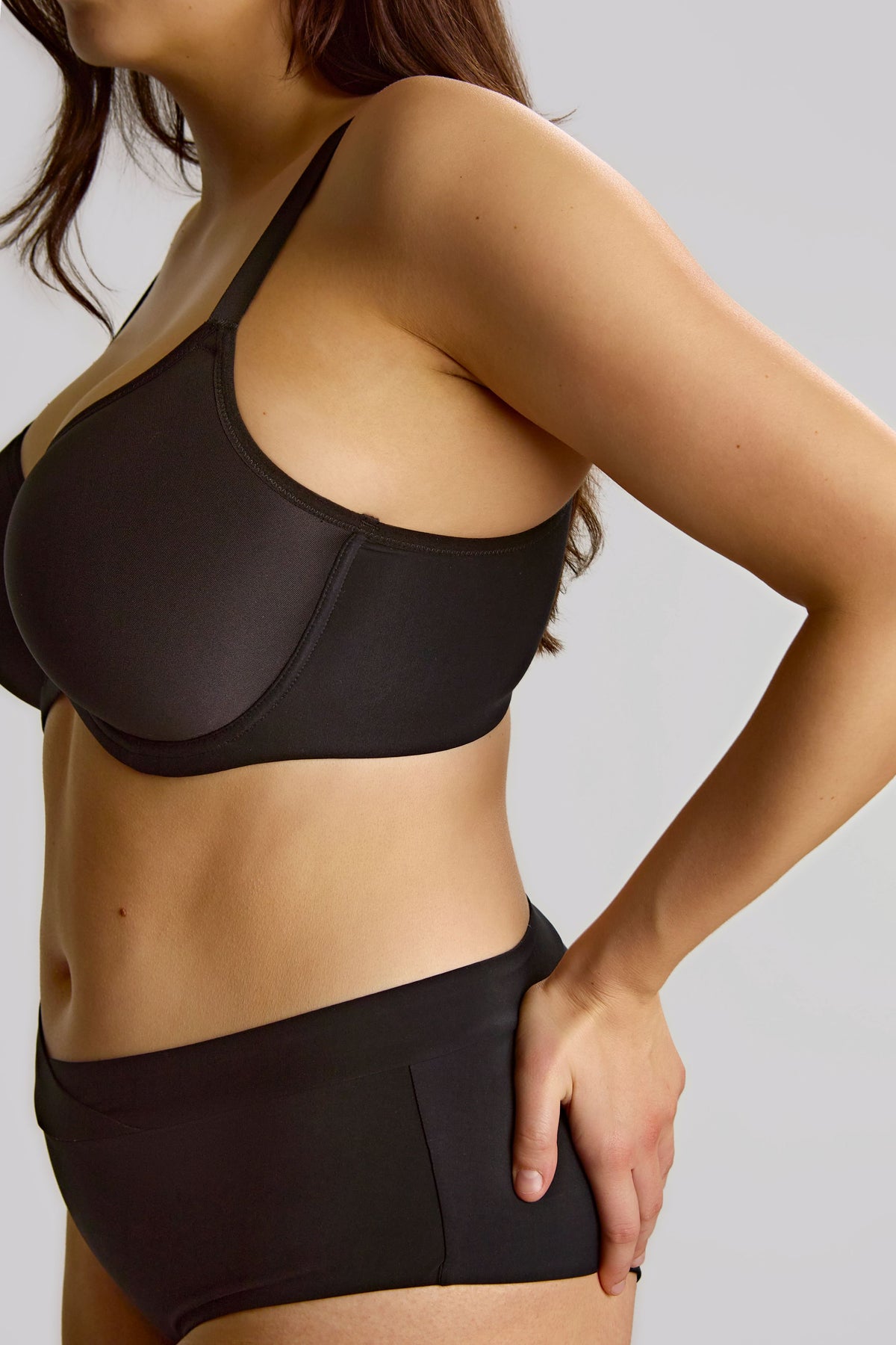 Person wearing a black bra and panty set on a plain background