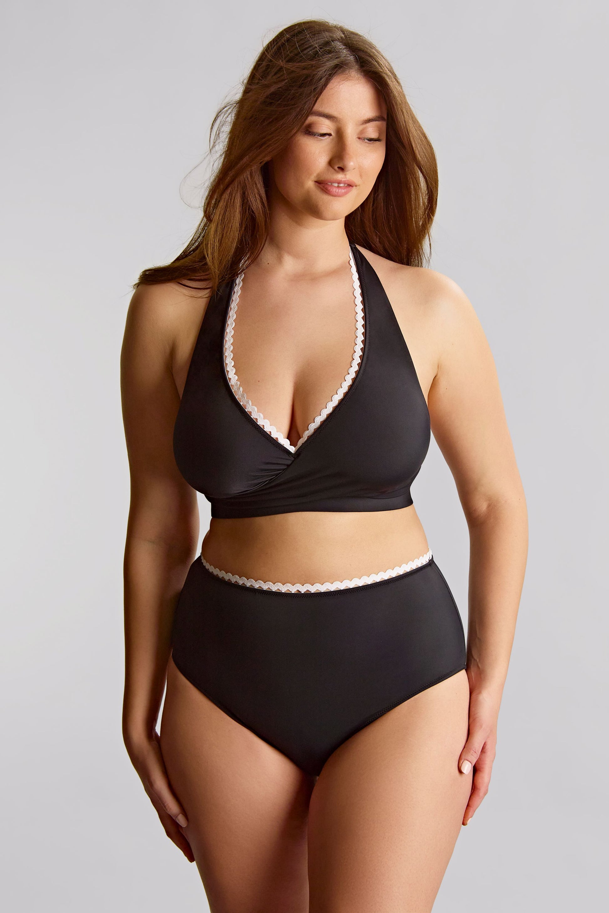 Woman wearing a black bikini with white lace trim against a gray background