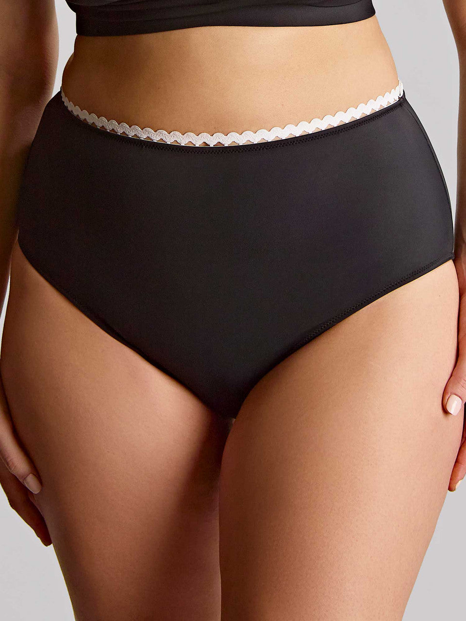 Black high-waisted bikini pant with white lace waistband on a neutral background