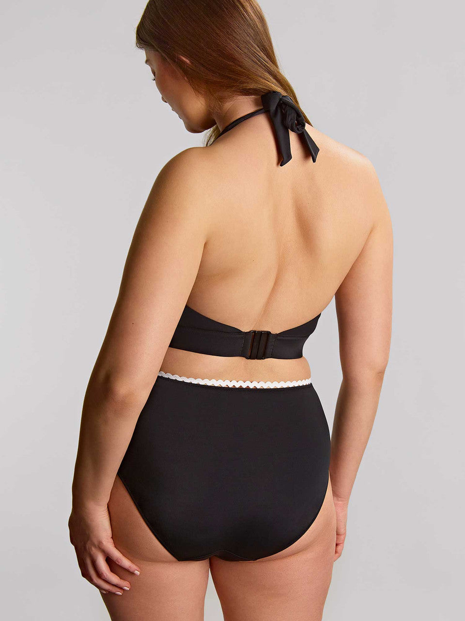 Woman wearing a black bikini with a white waistband on a gray background