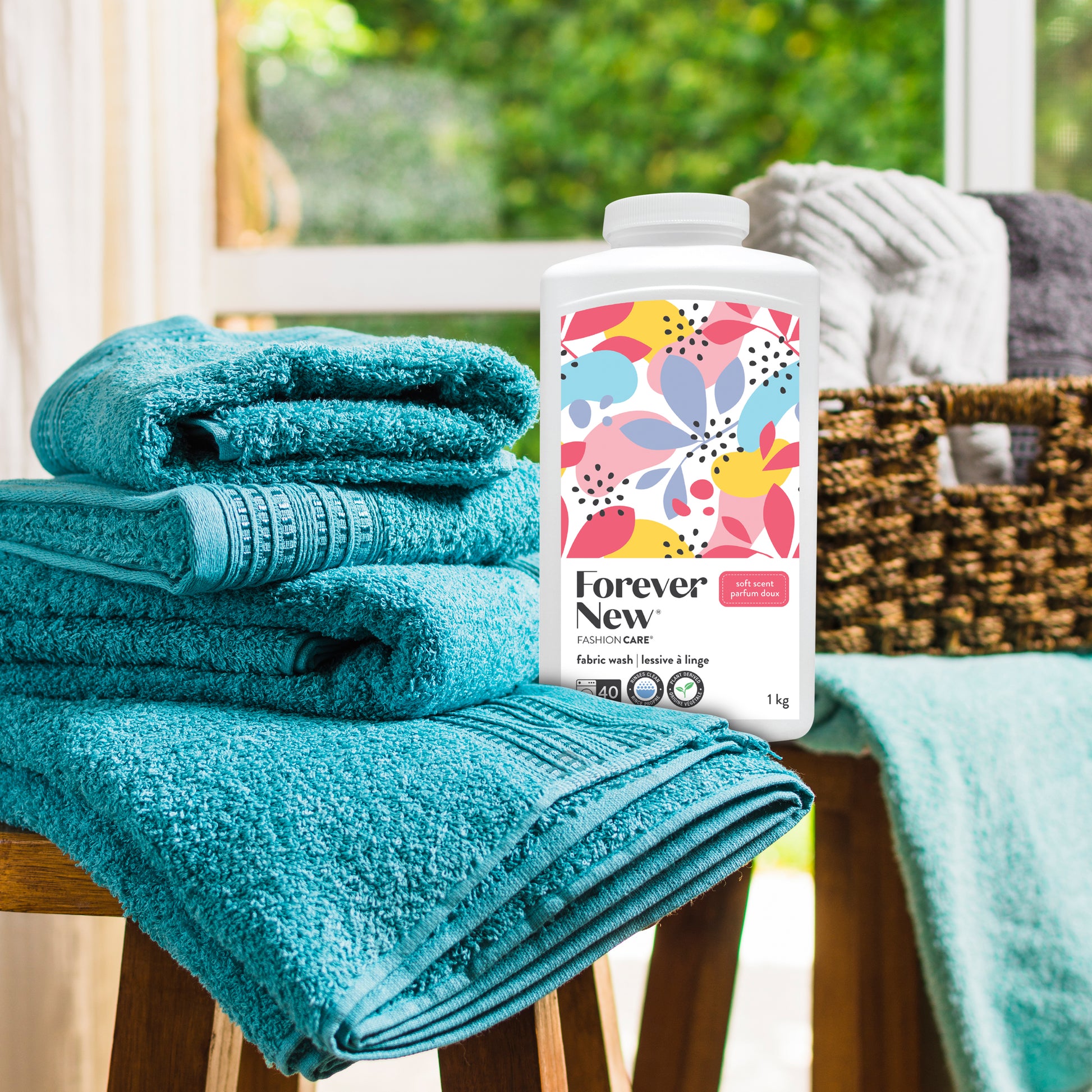 Forever New Powder Large Fabric Wash Soft Scent next to a stack of folded towels